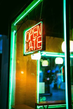 Penceresinde neon ışıkla asılı açık bir gece tabelasının dikey çekimi.
