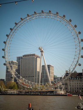 Arkaplanda nehir kenarında bir Londra gözü dönme dolap.