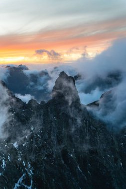Güneşin batışına karşı sisli dağ zirvesinin nefes kesici dikey görüntüsü