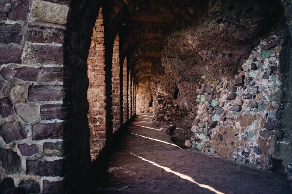 The interior of an old castle tunnel with stone walls and arches