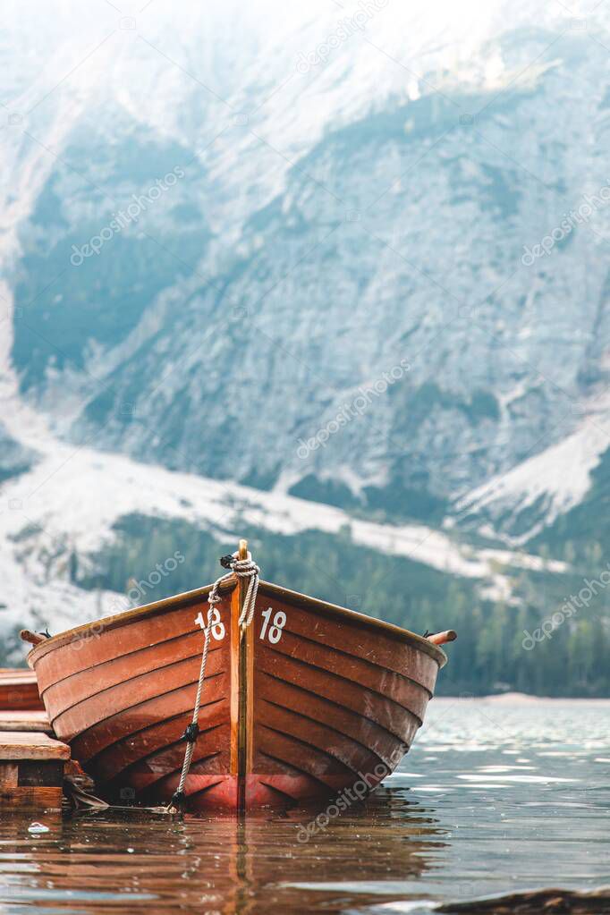 A vertical shot of a brown wooden row boat number 18 with a snow mountain background