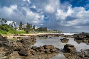 Queensland 'da büyüyen ağaçların arka planındaki kayalık sahilin havadan görünüşü