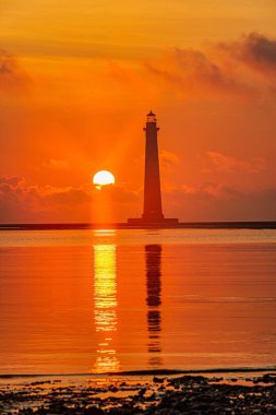 Turuncu bir günbatımında deniz feneri