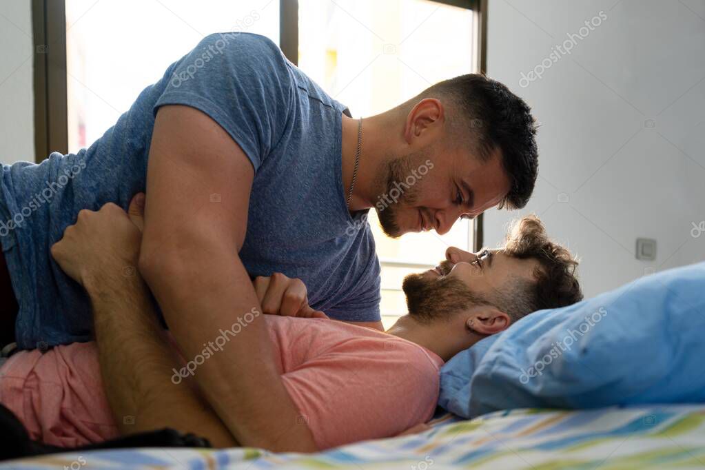 A gay couple lying on bed and looking each other