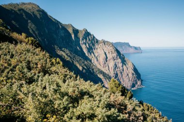 Mavi deniz ve gökyüzüne karşı kayalık kıyı şeridinin güzel manzarası. Madeira, Portekiz.