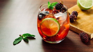 Böğürtlenli, üzümlü, otlu, limonlu ve buzlu bir kokteylin yakın plan fotoğrafı.