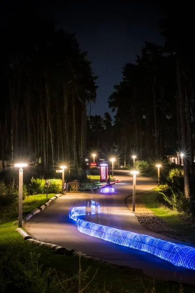 A vertical shot of bicycle light trails through a dark street at Centre Parcs Woburn with a phone booth in the background