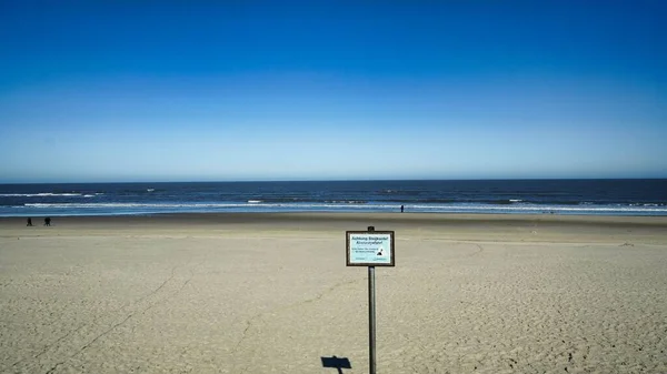 Μια Προειδοποιητική Πινακίδα Στην Αμμώδη Παραλία Στο Βάθος Της Θάλασσας — Φωτογραφία Αρχείου