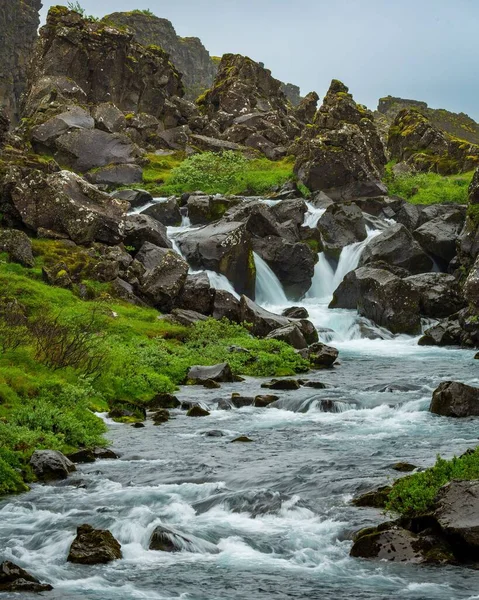 アイスランドの岩や草に囲まれた農村部を流れる川の垂直ショット — ストック写真
