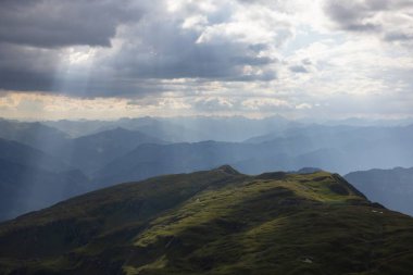 Bulutlu bir günde dağlara düşen güneş ışınlarının çarpıcı görüntüsü.