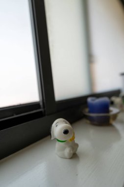 Pencerenin kenarına yerleştirilmiş küçük Snoopy Dog modelinin seçici bir odak noktası.