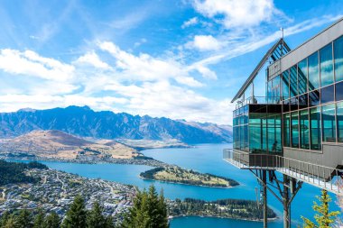 Queenstown, Yeni Zelanda 'daki bir tatil köyünün manzarası. Su birikintisinin üzerinde modern cam bir bina var.
