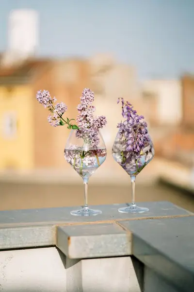 露台扶手上有水和紫丁香花的垂直镜片 — 图库照片
