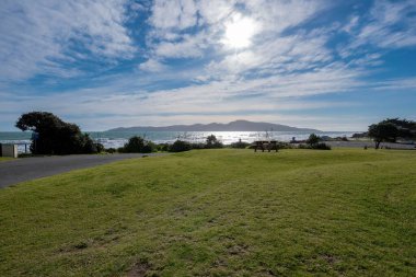 Raumati Sahili 'nde açık alan, önünde çimenler, Tazman Denizi ve Kapiti Adası, öğleden sonra güneşine bakıyor.
