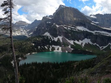 Dağların karla kaplı olduğu sakin bir göl manzarası.