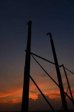 Gün batımında bulutlu güzel bir gökyüzüne karşı metalik direkleri alçak açıyla çekmek.