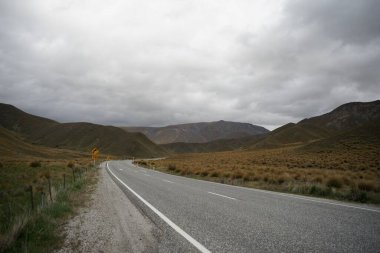 Bulutlu bir günde kuru tepe tarlasından geçen bir otoyol.