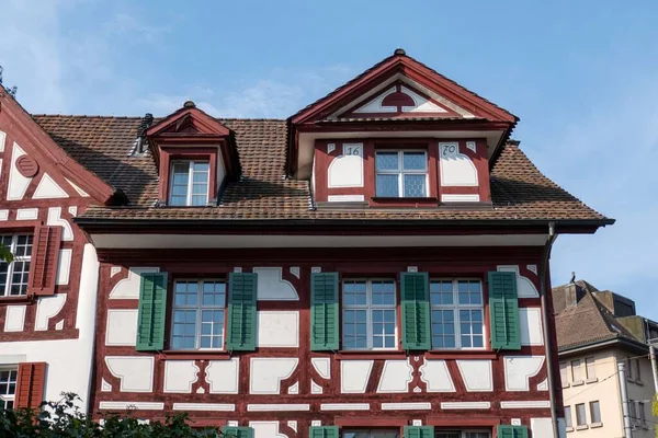 A traditional old house with windows and green wooden shutters in Switzerland
