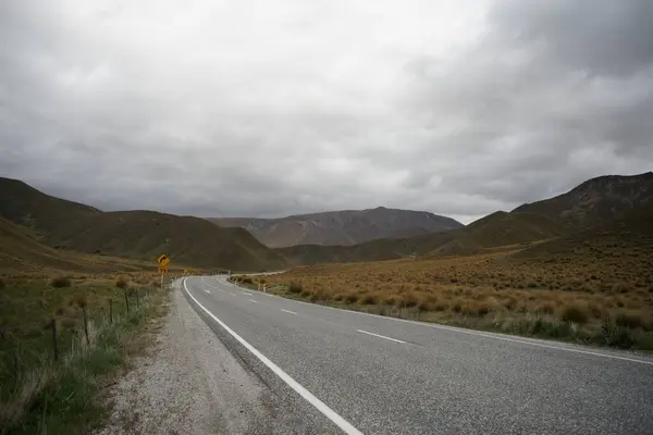 Bulutlu bir günde kuru tepe tarlasından geçen bir otoyol.