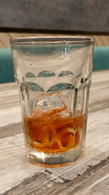 Buzlu çay ve ahşap bir masada eriyen buzlu bir bardak.