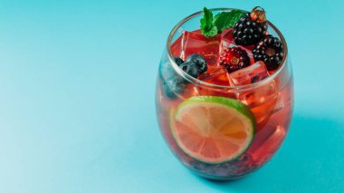 Böğürtlenli, üzümlü, otlu, limonlu ve buzlu bir kokteylin yakın plan fotoğrafı.