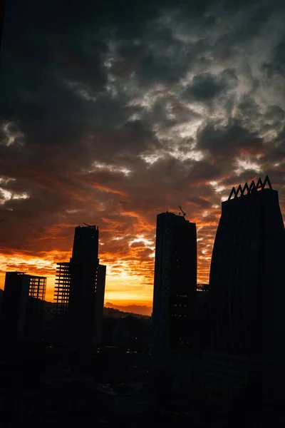 日没の建物のシルエットの垂直ショット — ストック写真