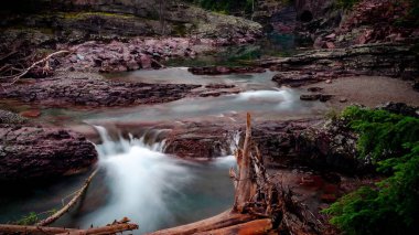 Montana 'daki Buzul Ulusal Parkı' ndaki kayaların arasından akan, nefes kesici bir dere manzarası.
