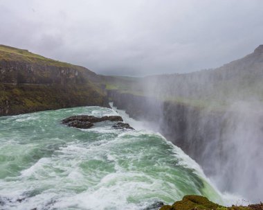 İzlanda 'daki Gullfoss Falls şelalesinin bulutlu arka planda kırsal bir alandaki manzarası.