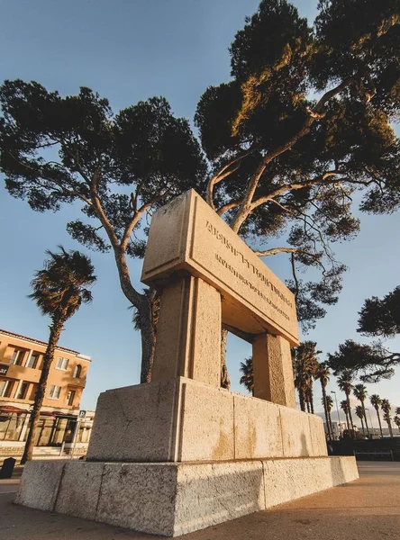 Ağaçlarla çevrili antik bir heykelin dikey görüntüsü.