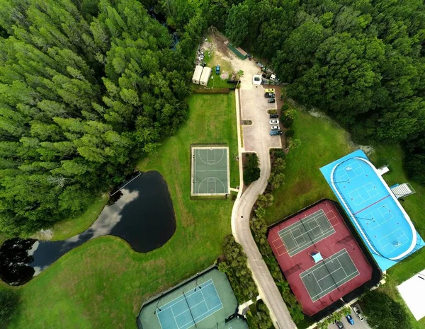环绕着绿林的职业网球场和篮球场的空中俯瞰 — 图库照片