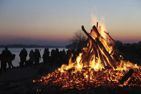 浜に立つ人々を背景にたき火を焼くの閉鎖 — ストック写真