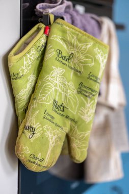 Mutfakta asılı bir çift yeşil fırın eldiveninin dikey görüntüsü.