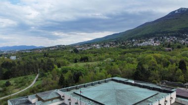 Mavi gökyüzünün altındaki dağlık bir arazide güzel bir şehir manzarası.