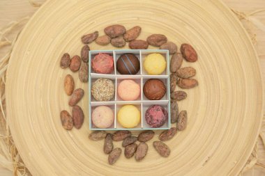 Yuvarlak gurme çikolataların farklı malzemelerle cevizlerle çevrili olduğu bir kutunun üst görüntüsü.