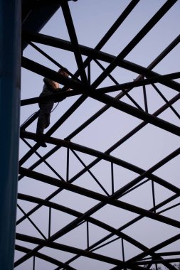 Bir tren istasyonunun metalik atari salonunda oturan beyaz bir erkeğin düşük açılı görüntüsü.