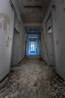 Terk edilmiş bir binada penceresi olan bir koridorun dikey görüntüsü.