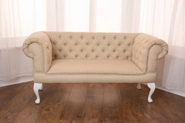 A stylish cream Chesterfield English sofa isolated in a bay window