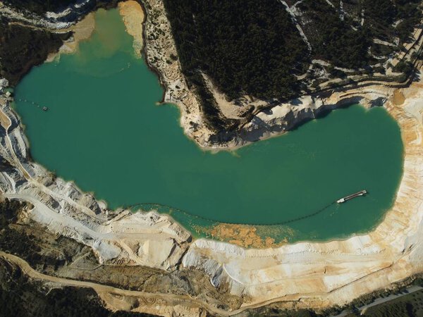 Вид с воздуха на зеленое озеро, окруженное песчаными холмами