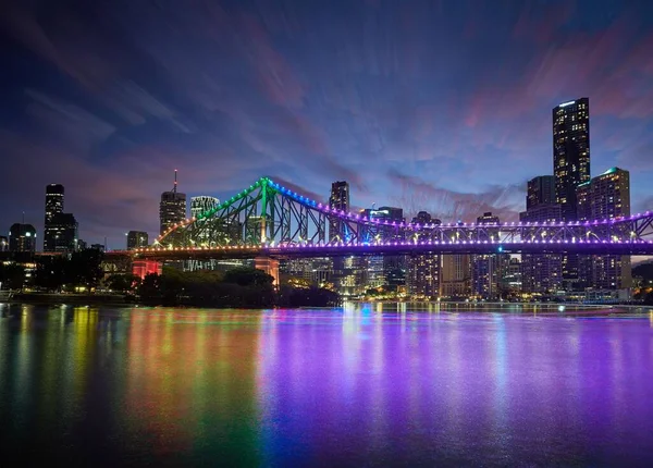 蓝色和紫色占支配地位 河流上的装饰与天空相抗衡 城市的灯亮着 故事桥上点缀着灯光 — 图库照片