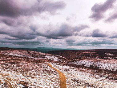 Hava aracı Shropshire dağlarında bulutlu bir gökyüzünün altında karla kaplı yürüyüş yollarını gösteriyor.