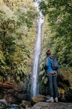 Portekiz, Madeira 'da güzel bir şelale manzarasının keyfini çıkaran sırt çantalı bir kadın.