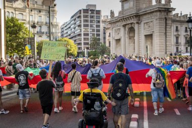 Eşcinsel Onur Yürüyüşü 'ndeki Protestocuların Resmi Tekerlekli Sandalyede İşlevsel Çeşitliliğe sahip Bir Kişiyle Dev Gökkuşağı LGBT Bayrağı Tutuyor