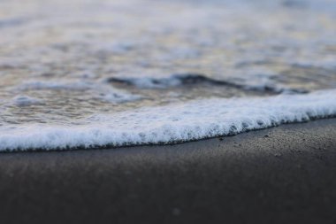 Siyah kumda köpüklü bir dalga.