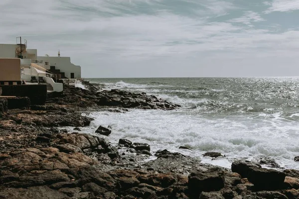 一个美丽的浪花在岩石海岸上 一艘船在地平线上 — 图库照片