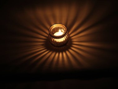 Dekoratif mum tutacağı yerde ve içinde yanan bir mum var.