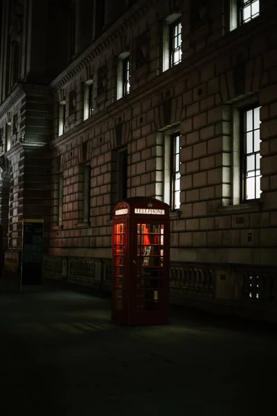 Gece Bir Binanın Önündeki Kırmızı Bir Telefon Kulübesinin Dikey Görüntüsü — Stok fotoğraf
