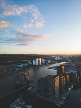 Ufukta nehir ve gün batımı olan şehrin manzarasının dikey görüntüsü.