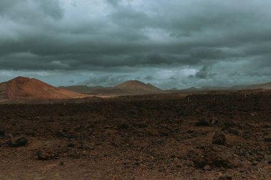 Kasvetli bir havada tepeleri olan düz bir arazi.