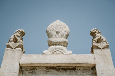 TianYi Mezarı, Pekin, Çin 'deki mavi gökyüzü arka planında oyulmuş heykellerin düşük açılı bir görüntüsü.