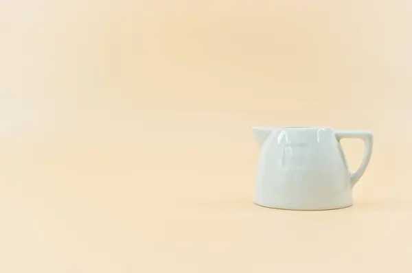 Weißes Porzellan Milchkanne Isoliert Auf Einem Pfirsichfarbenen Hintergrund Mit Kopierraum — Stockfoto